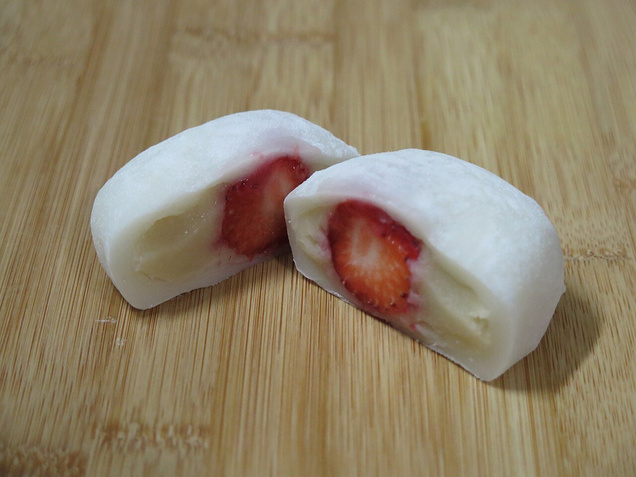 Korean fruit mochi cut in half showing a whole strawberry inside