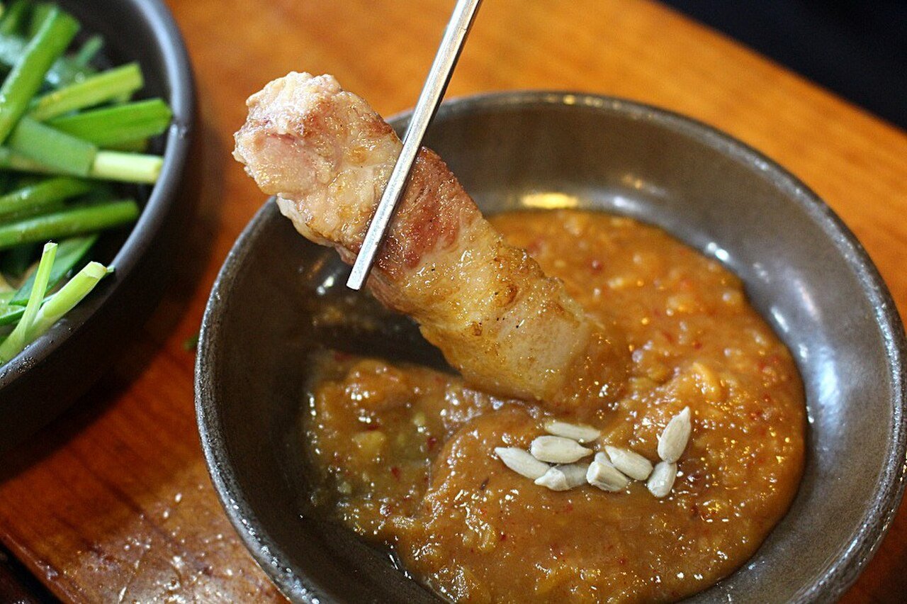 Dipping a piece of grilled samgyeopsal into ssamjang soybean chili paste