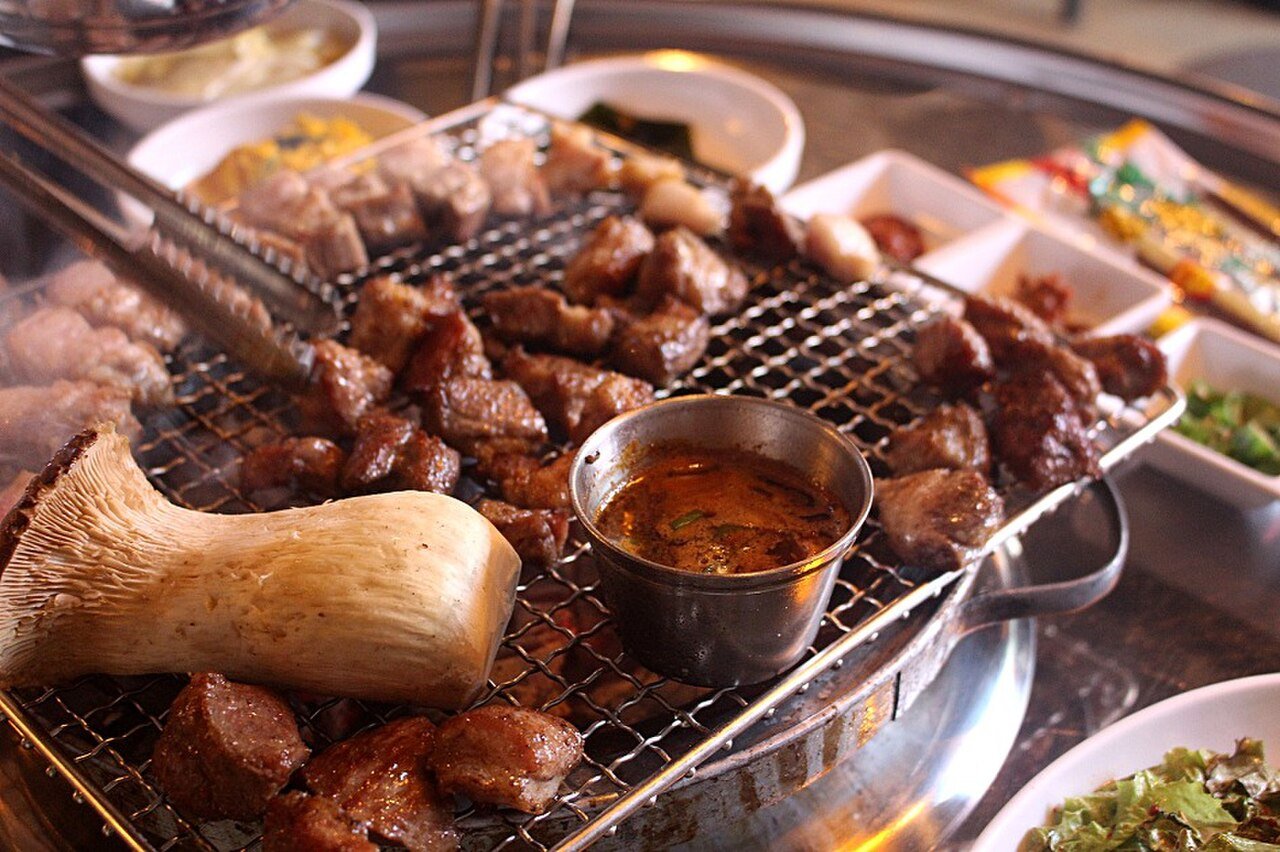 Pork neck moksal, samgyeopsal, king oyster mushrooms and meljeot anchovy sauce on a Korean BBQ grill