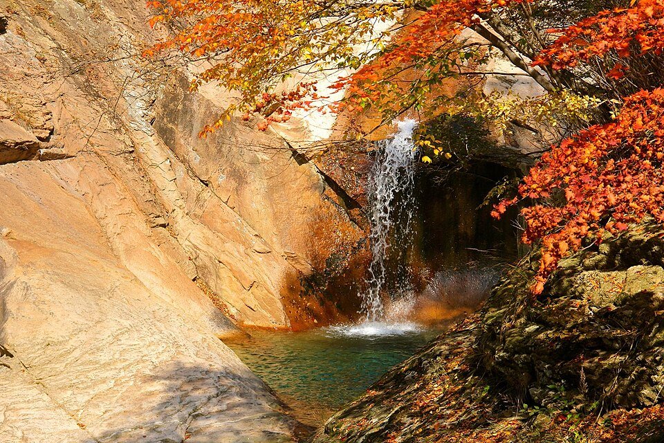Waterfall framed by red maple leaves in a Seoraksan valley in autumn