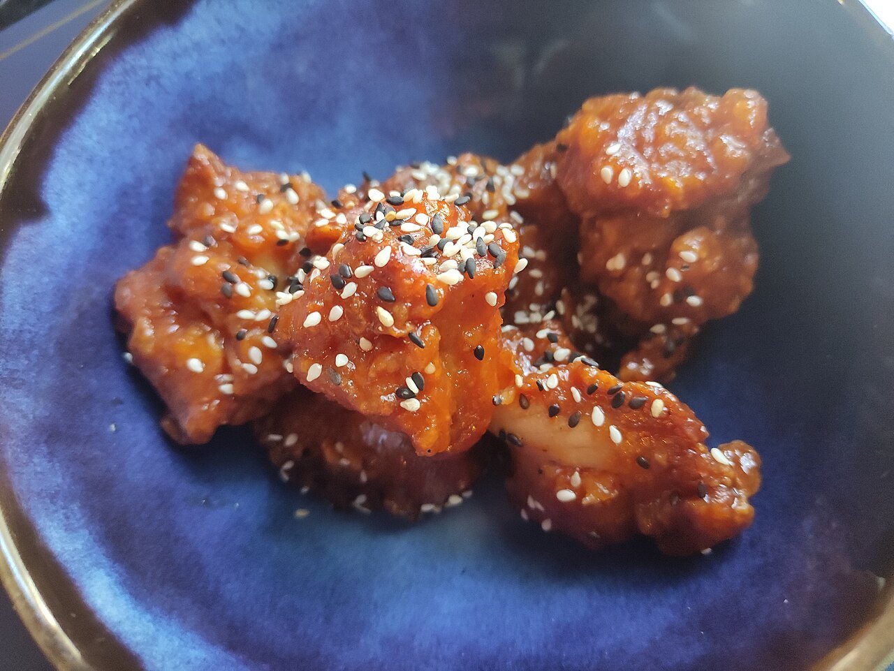Close-up of glazed yangnyeom Korean fried chicken with sesame seeds